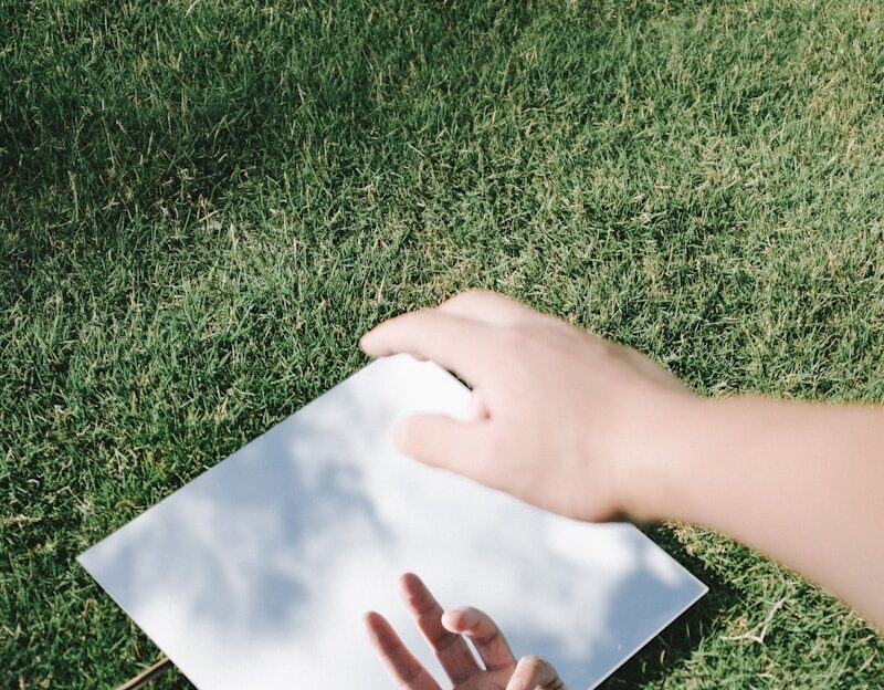 Photo by - Kenny A hand reflects in a mirror on grass.