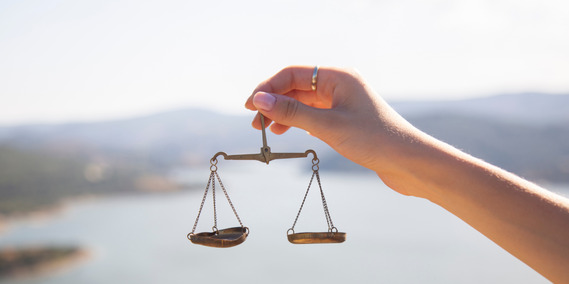 A hand reflects in a mirror on grass.